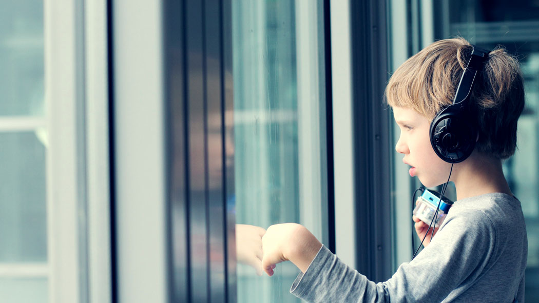 Junge mit Kopfhörern schaut aus dem Fenster | Foto: 70637464 | © dubova